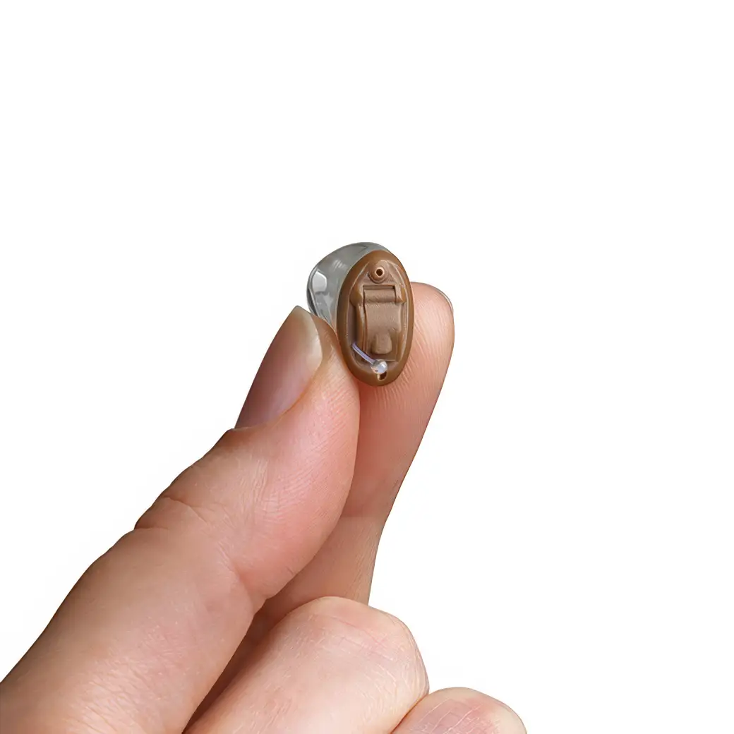Hearing aid held between a person's fingers, showcasing its small size and design.