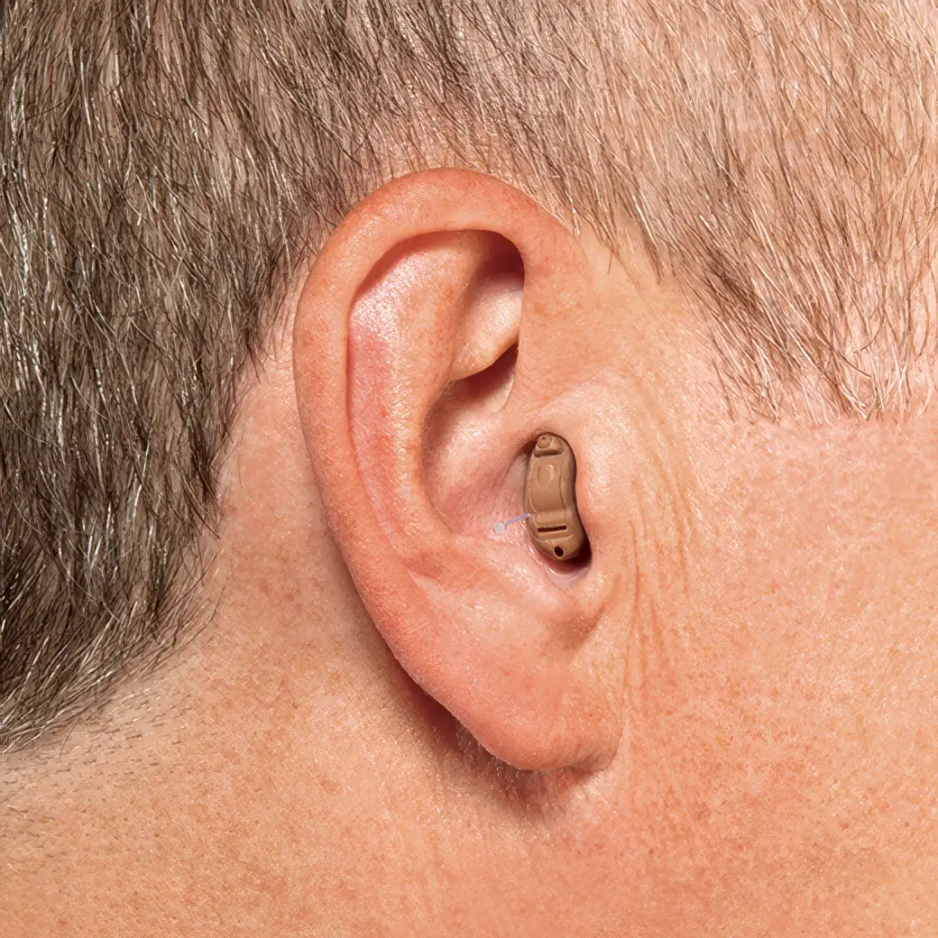 Close-up of a person's ear with a hearing aid inserted, showcasing the device positioned behind the ear.