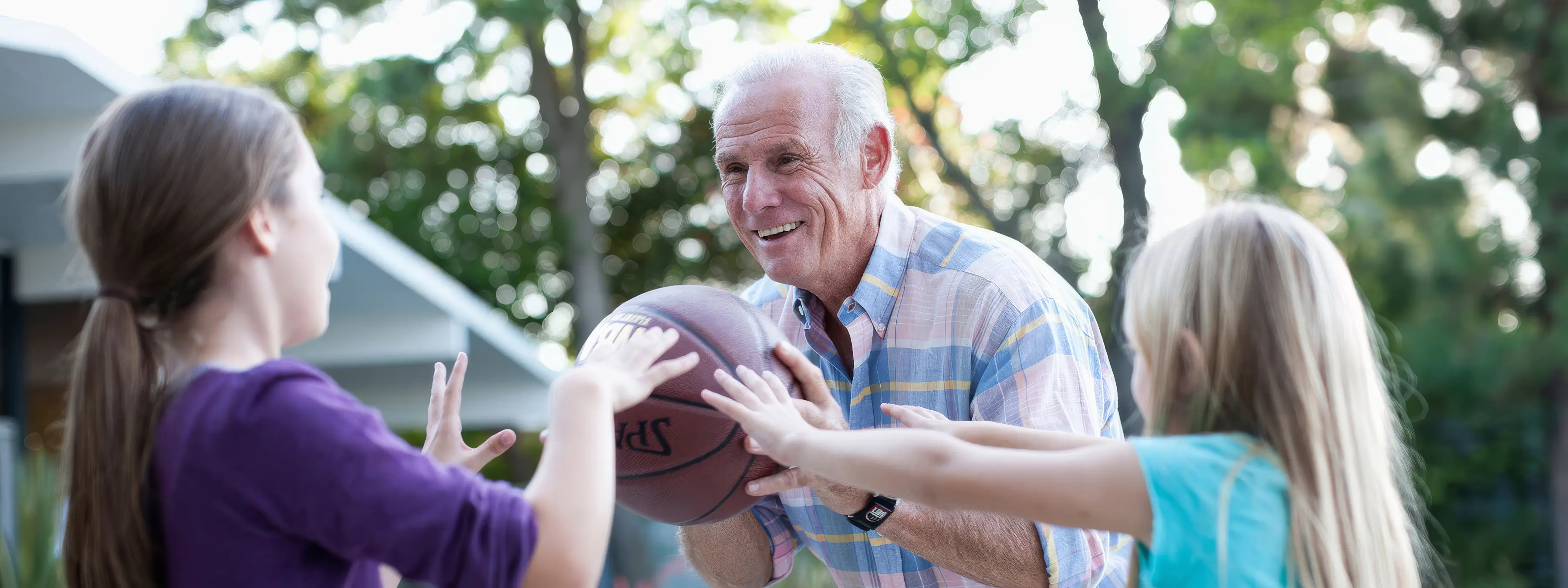 Grandfather playing basketball with grand children